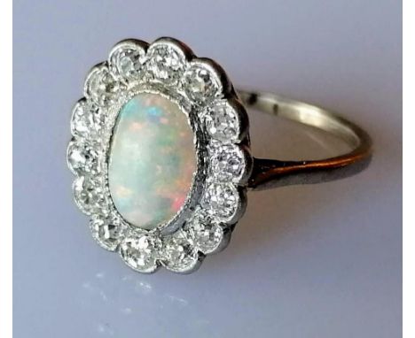 An oval opal (9mm x 6mm) cluster ring with 14 round brilliant-cut diamonds, total approximate diamond weight 1 carat, on a wh