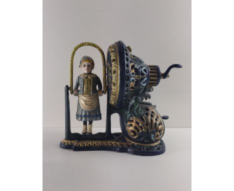 Cast metal money box in the form of a young girl skipping with rope, mechanical crank operation. In working order. Shipping G