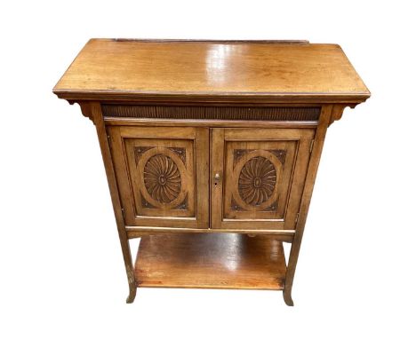 Arts and crafts walnut cabinet, with projecting top and enclosed by pair of oval patera carved panel doors, with shelf below,
