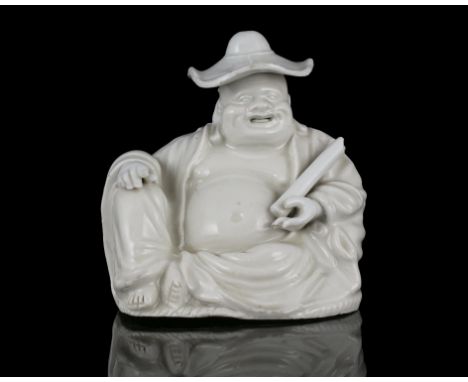 A BLANC DE CHINE / DEHUA PORCELAIN MODEL OF A SEATED BUDAI WEARING A HAT AND HOLDING A SCROLL CHINA, QING DYNASTY H: 14,8 cm 
