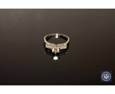 A diamond solitaire ring, a brilliant-cut diamond within a raised claw setting upon diamond set shoulders, to a plain shank, 