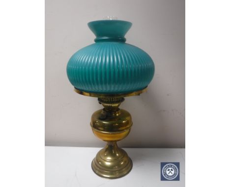 An early 20th century brass oil lamp with chimney and green glass shade 