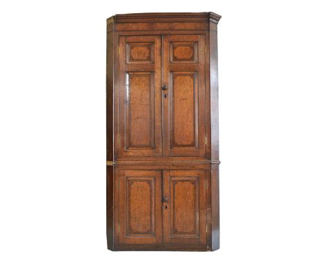 George III oak floor standing double corner cupboard, dentil cornice above a pair of doors with two raised and fielded panels