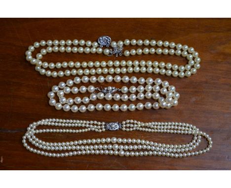 A triple row of graduated cultured pearls knotted throughout onto oval pearl-set clasp stamped 9ct; a row of uniform cultured