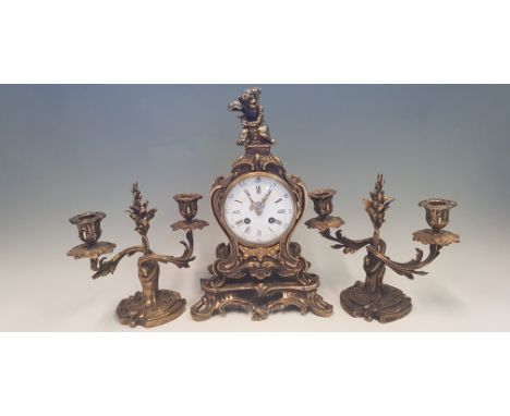 A brass cased mantel clock with cherub holding grapes to top, height 35cm, together with a pair of twisted garniture candlest
