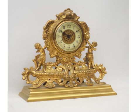 Late 19th century gilt metal mantel clock, ornate cartouche shaped with putto figures, floral and trailing foliage decoration