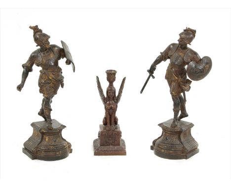 Two spelter figures modelled as classical warriors, together with a figural spelter candlestick in the form of a sphinx upon 