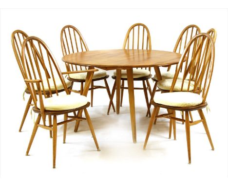 An Ercol elm circular dining table, with two flaps and a set of six stick back Windsor chairs, 113cm diameter