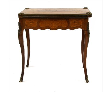 A French Louis XV style walnut card table, the fold-over rectangular top with marquetry inlaid decoration and gilt metal moun