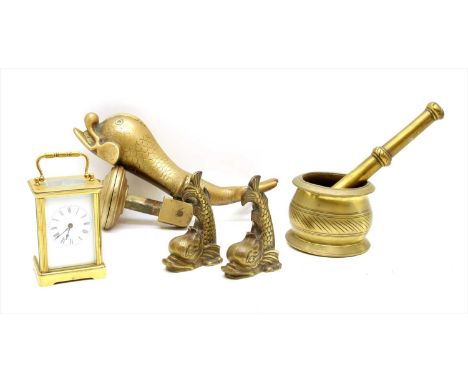 A collection of brass items, comprising a dolphin shaped door knocker, two matching doorstops, a carriage clock and a pestle 