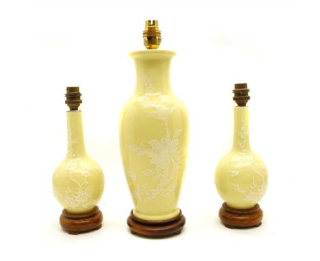 A Chinese porcelain pâte-sur-pâte lamp garniture, each with white birds and blossom decoration on a yellow ground (3)