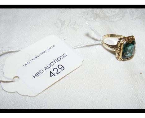 A rectangular green stone dress ring in gold setting 