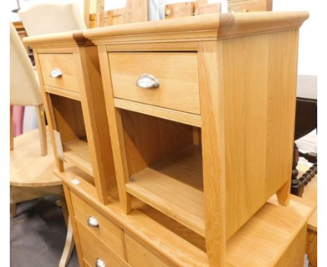 A pair of light oak bedside cabinets each with a frieze drawer and a recess and a label for a Bentley Designs.