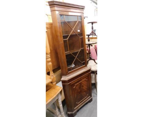 A mahogany standing corner cabinet with a single glazed door and a panel door on bracket feet. 