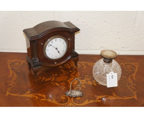 An Edwardian mahogany mantel clock with shallow moulded domed top, white enamel dial with Arabic numerals, flanked by fluted 