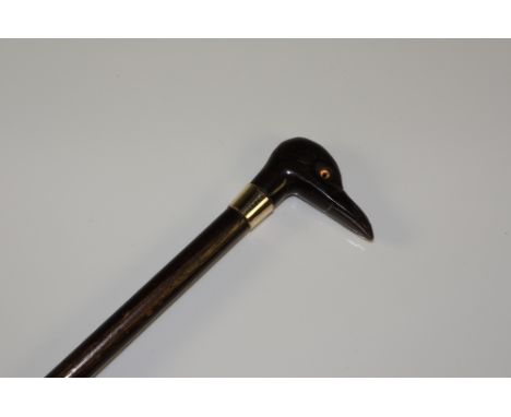 An unusual child's walking stick with stylised bird's head horn terminal, glass eyes, gold coloured metal collar, ebonised sh