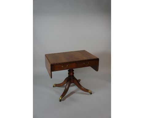 A Regency mahogany sofa table the rounded rectangular top with reeded lip above two short drawers, turned column on four outs