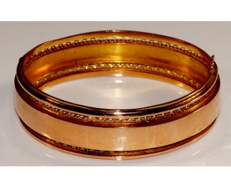 A 19th Century French 18 ct gold bangle the central plain band within borders of continuous pierced vitruvian scrolls, moulde