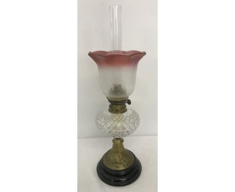 A vintage oil lamp with glass bowl and clear & cranberry coloured etched glass shade. Mounted on black ceramic base and compl