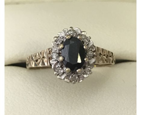 A 9ct gold sapphire dress ring. Central oval blue sapphire surrounded by illusion set 8 small white sapphires. Size L 1/2.