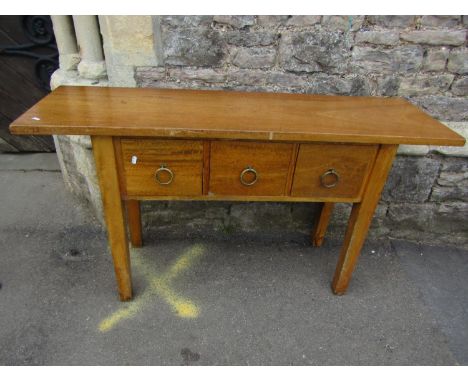 A contemporary hardwood side/serving table of rectangular form with overhanging top over three deep frieze drawers with brass