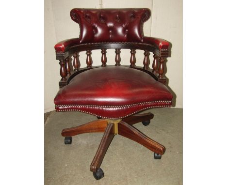 A pair of contemporary reproduction swivel office desk chairs with maroon coloured leather upholstered seats and button backs