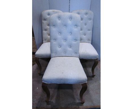 A set of four contemporary dining chairs with linen upholstered seats and high rounded button backs raised on cabriole forele