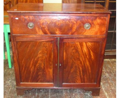 A Georgian mahogany cupboard enclosed by a frieze drawer and a pair of panelled doors raised on bracket supports, the interio