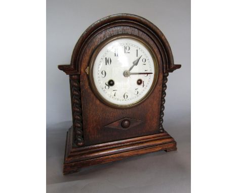Oak cased twin train arch shaped mantle clock with turned barley twist pilasters, the two train enamel dial with Arabic numer