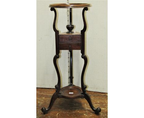 A Georgian mahogany washstand with moulded circular open basin supported over two small drawers and scrolled supports 