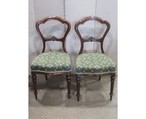 A set of four Victorian walnut balloon back dining chairs with moulded frames, tapestry upholstered seats with serpentine fro
