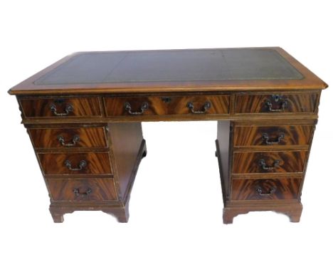 A mahogany pedestal desk in George III style, the top with a green leather inset and canted corners, above an arrangement of 