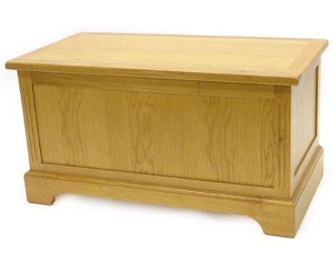 An ex shop display natural oak blanket box or toy box, with hinged lid and a panelled front on bracket feet, 95cm W.
