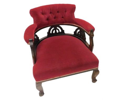 An Edwardian mahogany tub shaped chair, with buttoned upholstery in red fabric on cabriole legs with ceramic castors.
