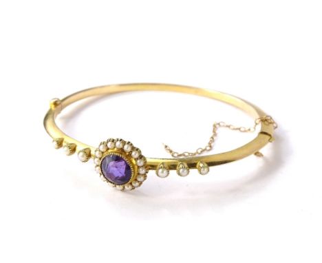 A Victorian amethyst and seed pearl hinged bangle, with circular faceted amethyst stone, surrounded by seed pearls, with thre