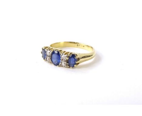 A sapphire and diamond dress ring, set with three oval cut sapphires each in claw setting, broken by two rows of two round br