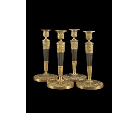 GRUPPO DI QUATTRO CANDELIERI XIX secolo Bronzo dorato e dipinto, a colonna, con decoro a palmette e foglie d'acqua. 25 x 12,5