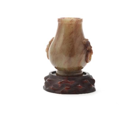 A Chinese jade hu-form vase, the bulbous body raised on a splayed foot, the shoulder flanked by a pair of beast mask handles 