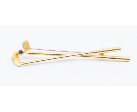 Golfing interest- a 18ct gold and sapphire set golf club, comprising two golf clubs with a ball inset with a faceted sapphire