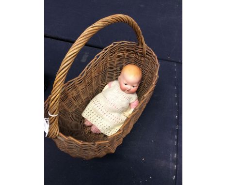 A 1920's bisque baby doll, Armand Marseille, in vintage basket