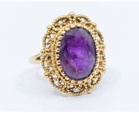 An amethyst and 9ct gold dress ring, comprising an faceted oval amethyst, approx 9 x 13mm, within a fancy rope and bead borde