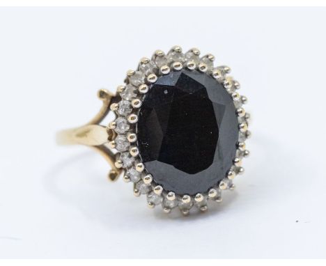 A sapphire and diamond 9ct gold cluster ring, comprising a dark blue oval cut sapphire approx 9 x 11mm, within a border of sm