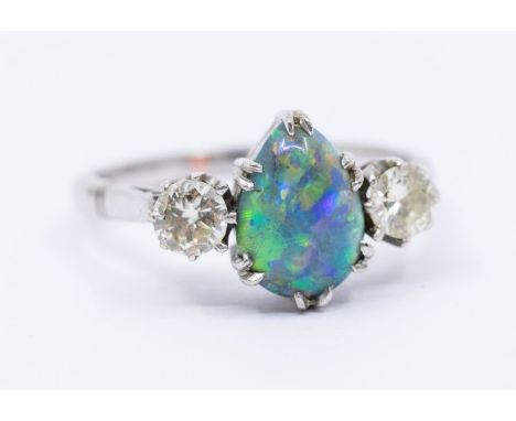 An opal and diamond three stone 18ct white gold ring, comprising a pearl cut black opal to the centre, with green, orange, bl