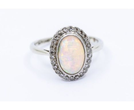 An Edwardian opal and 18ct white gold and platinum ring, comprising a central oval opal within a border of eight cut diamonds