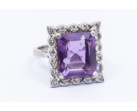 An amethyst and diamond 18ct white gold ring, comprising a rectangular amethyst claw set within a border of small diamonds wi