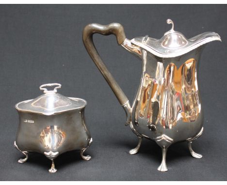 A silver café au lait pot, with lobed body, wooden handle and supported on four legs, with a matching sugar basin with hinged