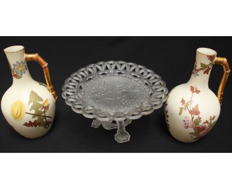 A pair of Royal Worcester ivory ground jugs decorated with flowers (AF), together with a frosted and moulded glass tazza. (3)