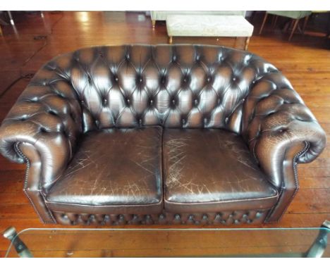 A brown leather button back Chesterfield two seater sofa, approx 