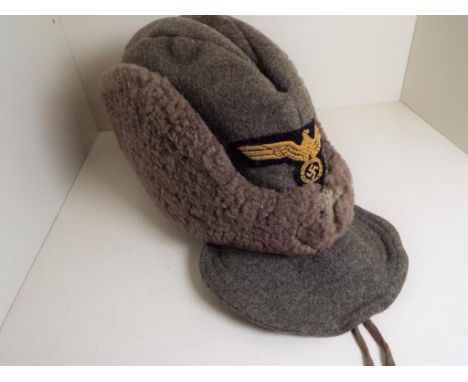 World War Two (WW2) - a German winter hat with eagle, swastika and laurel wreath patch badge to the fore - NOTE: Please read 