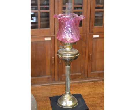 A tall late Victorian/Edwardian brass table oil lamp, cranberry glass shade, c.1900